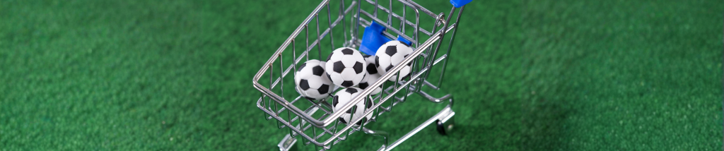 Carrinho de compras com bolas de futebol sobre gramado verde, ilustrando estratégias de vendas para a Copa do Mundo no e-commerce.